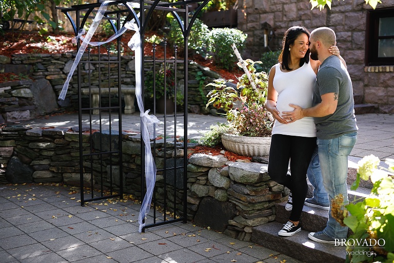 Pregnant couple posing by wedding arch at Van Dusen mansion