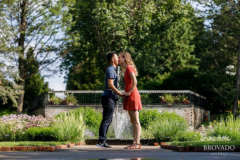 Couple kissing in front of landscape arboretum fountain
