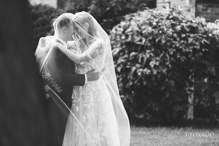Sarah and Chris pose under bride's veil in black and white