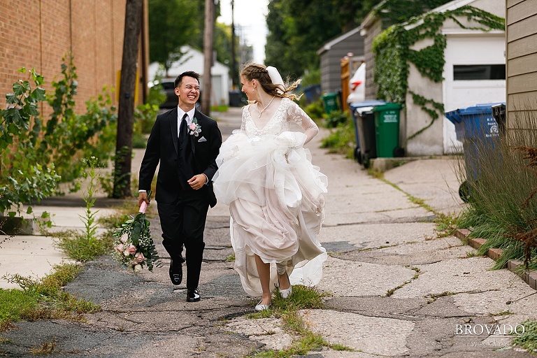 Bride and groom running through south minneapolis alley