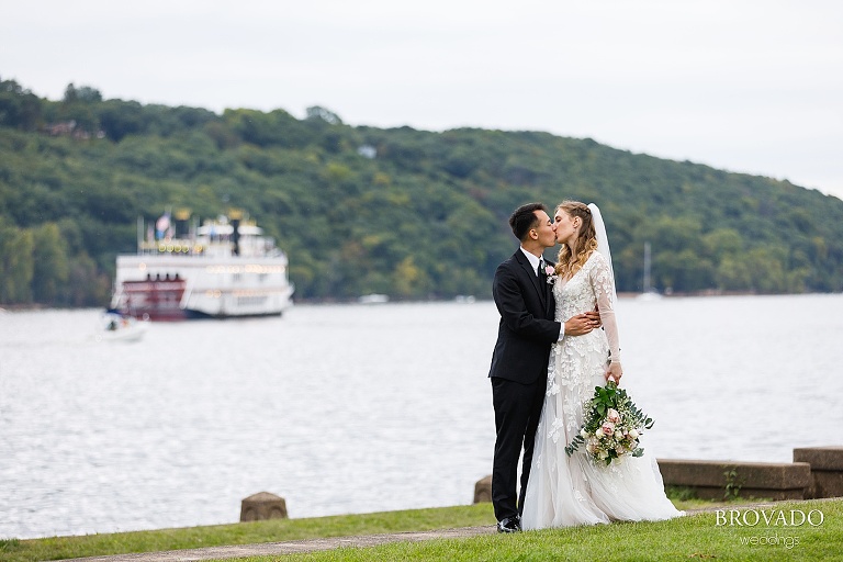 Bride and groom kissing on the bank of the st croix river in Stillwater