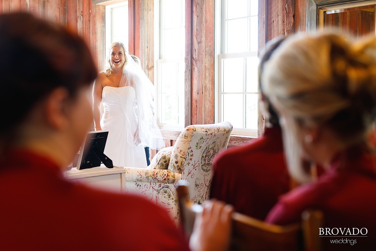 Bride laughing while her mother puts on her dress