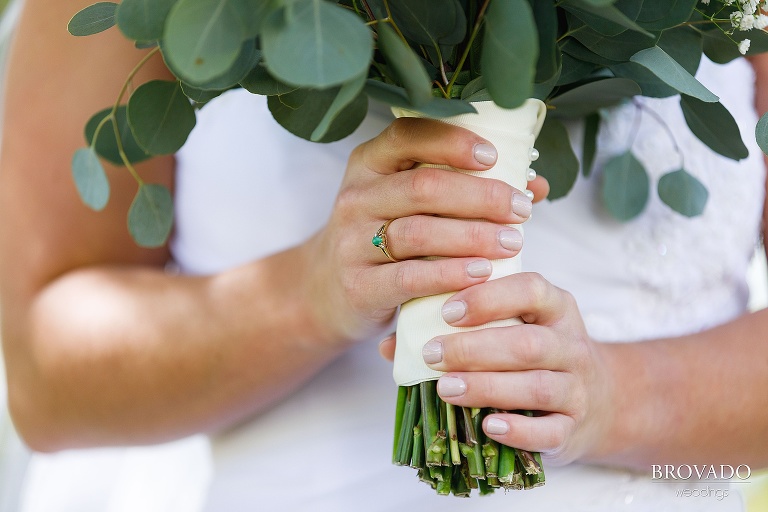 Closeup of bride's green ring holding her bouquet