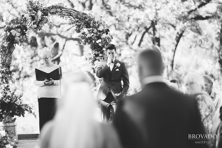 Groom crying while bride walks down the aisle
