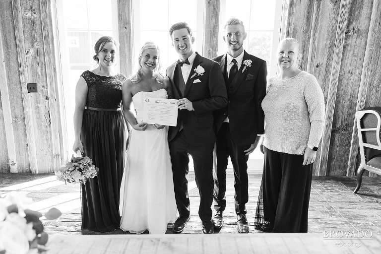 Officiant, bride, groom, maid of honor, and best man holding wedding certificate