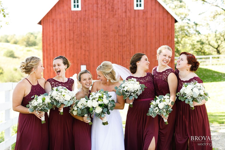 BRidesmaids laughing together in front of red barn