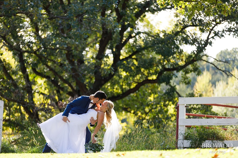 Groom dipping the bride in front of almquist farm fence