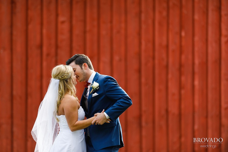Bride and groom kissing in front of red barn