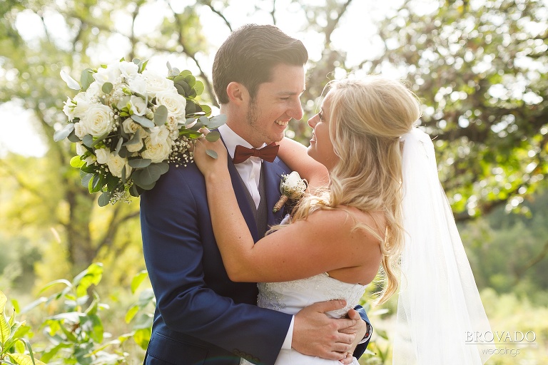 Bride and groom embracing in bright field