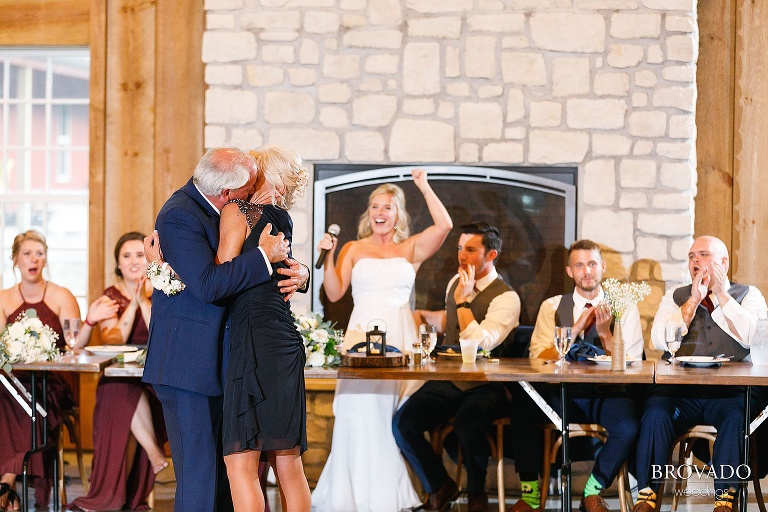 Bride cheering as her parents kiss during wedding reception