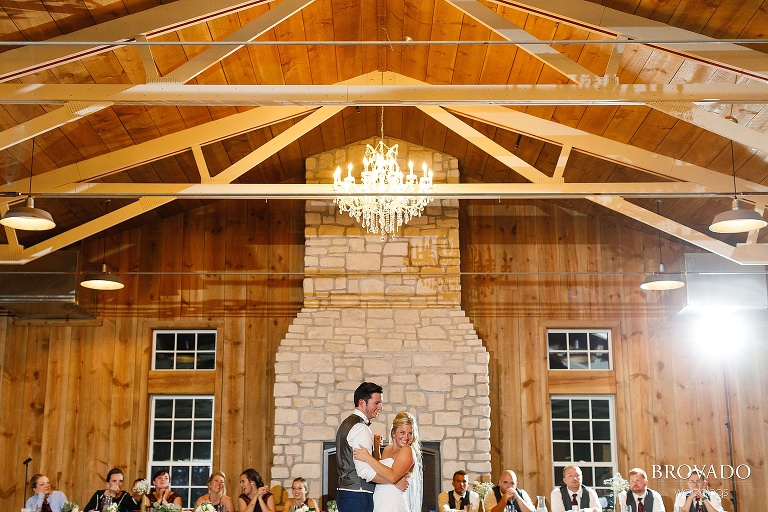 Bride and groom smiling at crowd during first dance