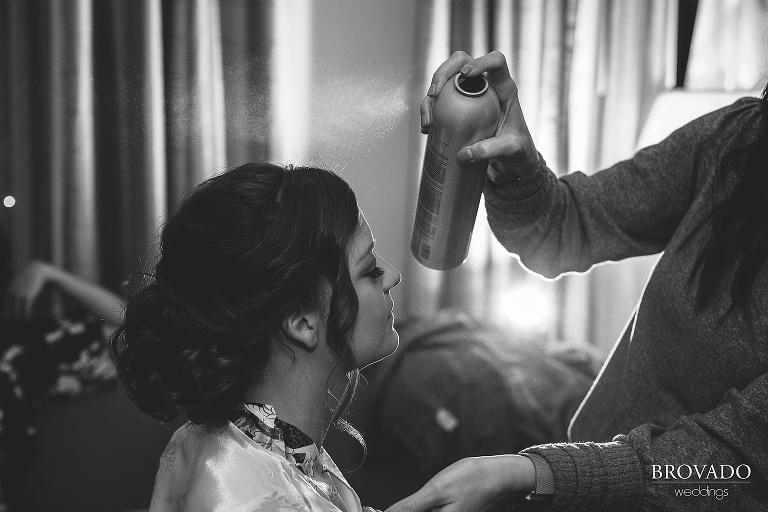 Black and white image of bethany having her wedding updo hairsprayed