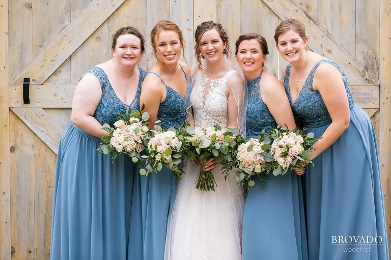 Heather and her bridesmaids smiling in front of a barn door