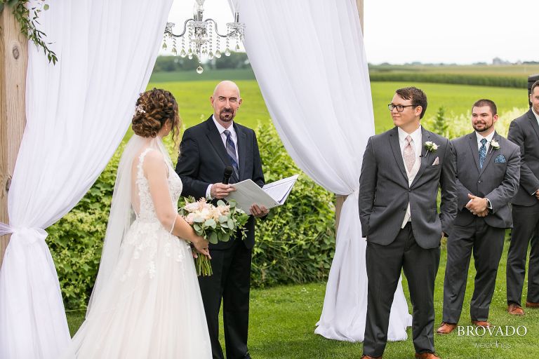 Officiant smiling at bride and groom during wedding ceremony