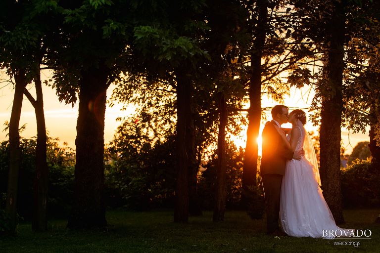 Bright sunset peeking out behind Heather and Daniel kissing