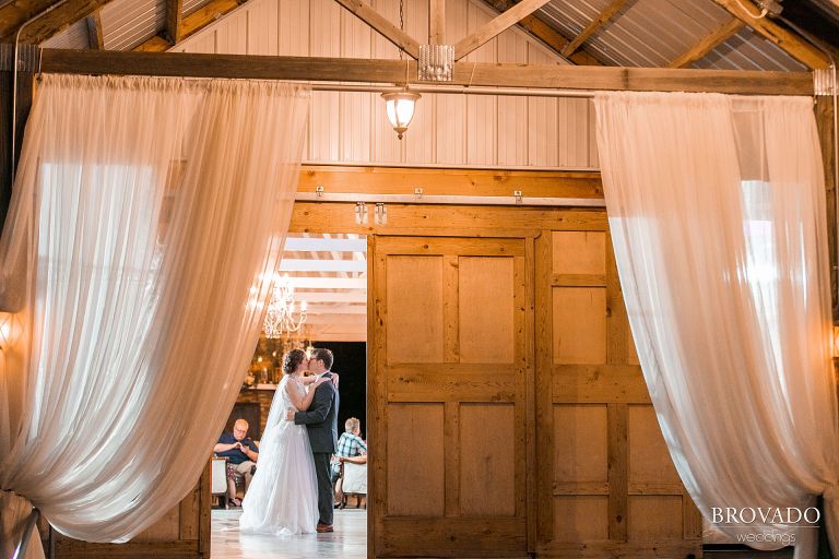 Bride and groom dancing and kissing through barn doors