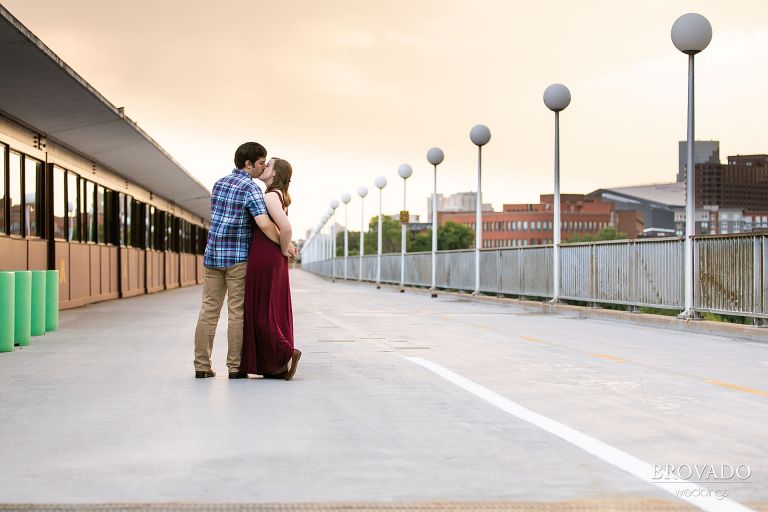 Engaged couple kissing in front of sunset