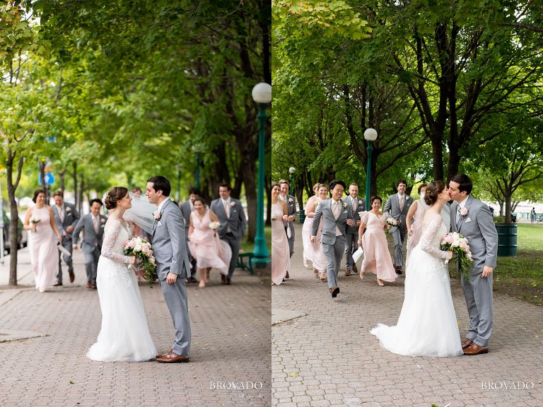 Wedding party running towards kissing couple