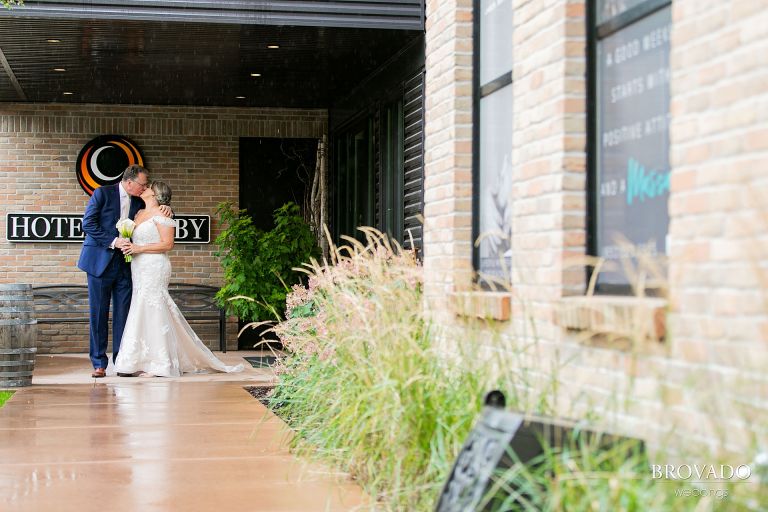 Bride and groom kissing outside of hotel crosby