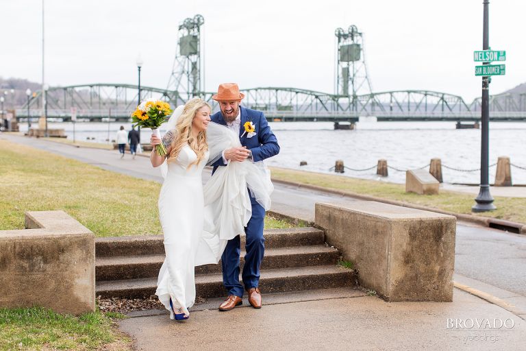 Groom helping bride walk down stairs