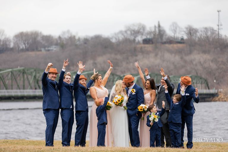 Wedding party cheering while bride and groom kiss